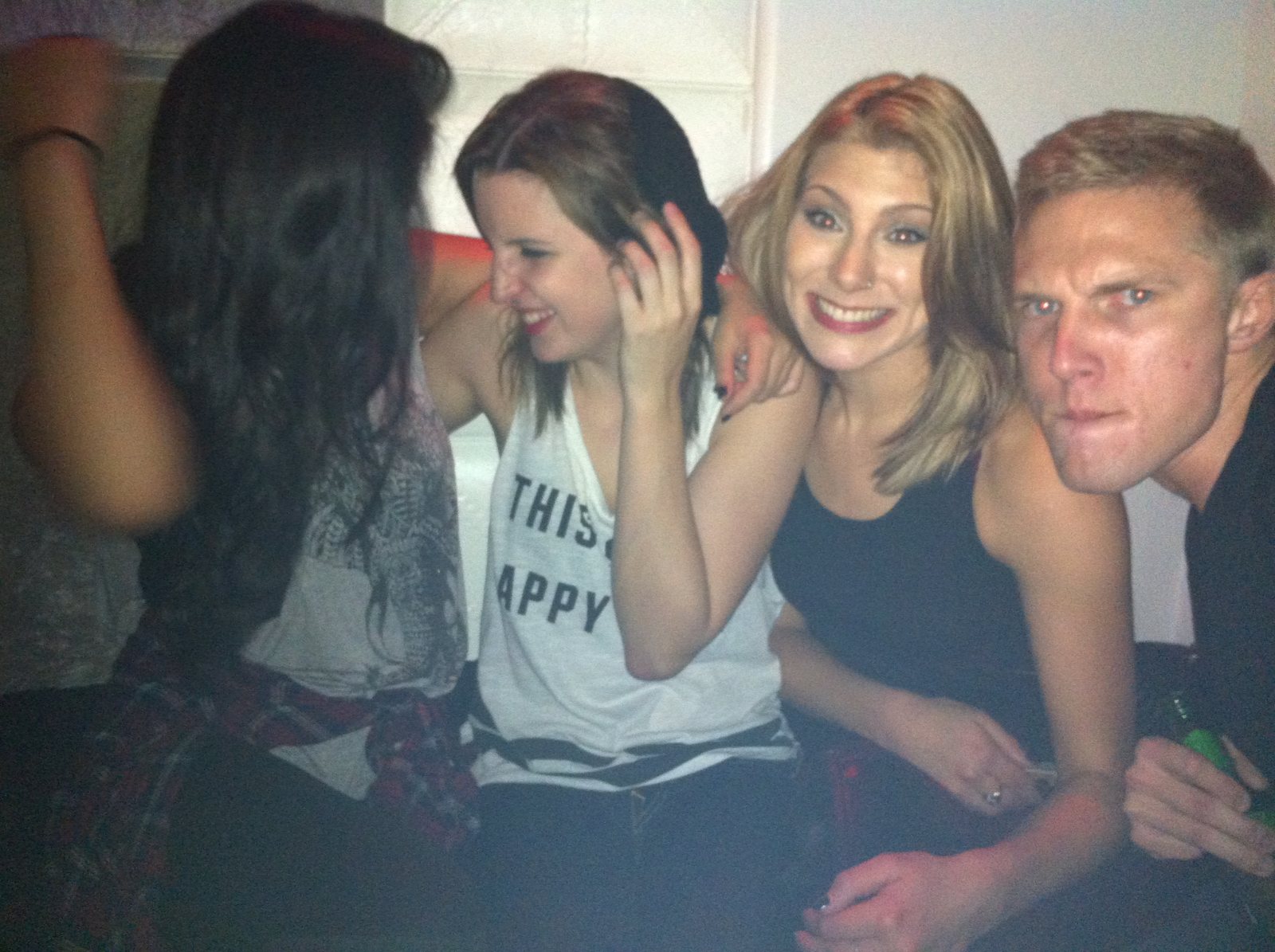 Three friends smiling together beneath club lights