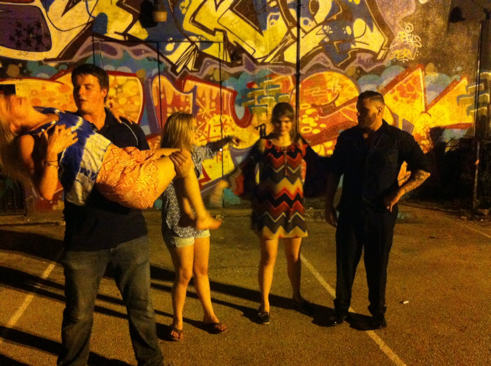 A full group portrait in front of a painted city mural