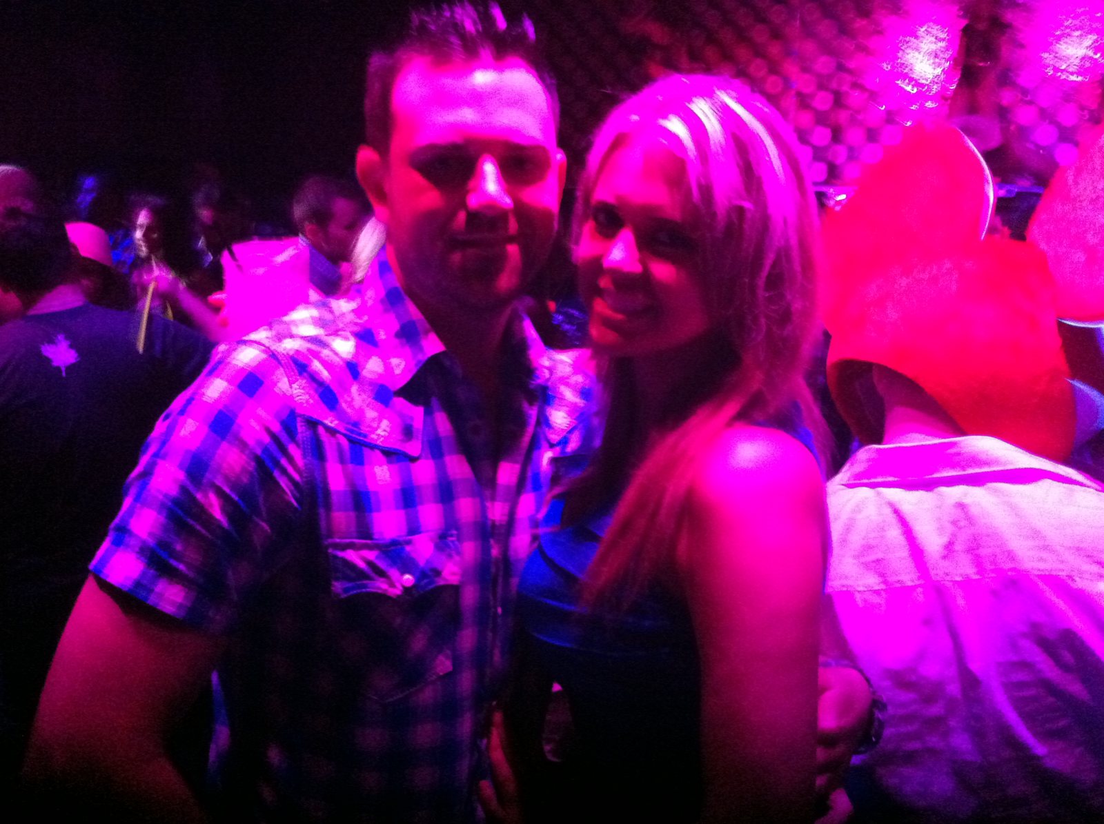 Two friends caught beneath vivid purple club lights