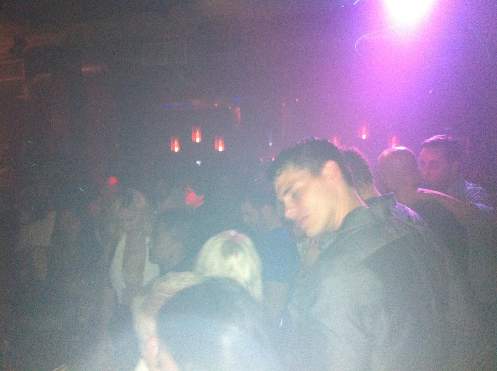 Guests moving through a club beneath purple haze